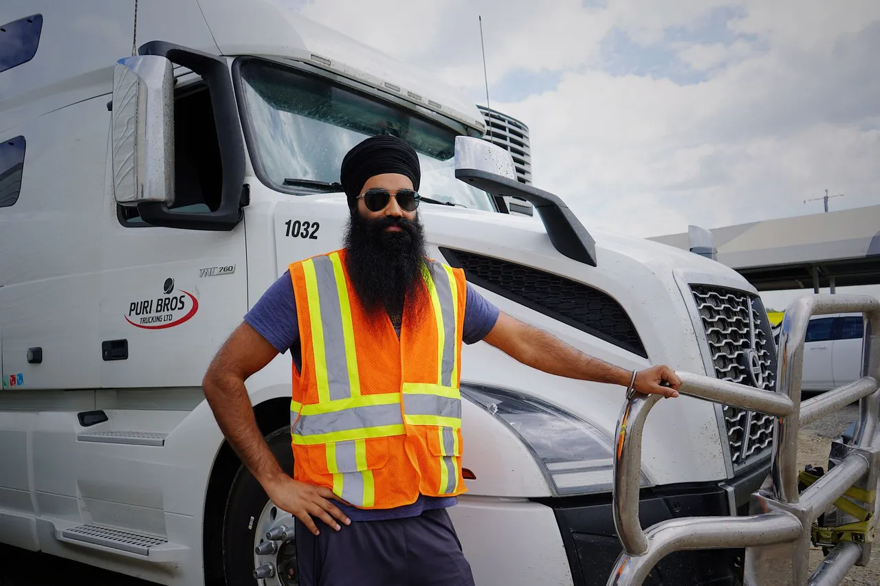 A truck driver in high-visibility gear unloading cargo at an industrial facility.