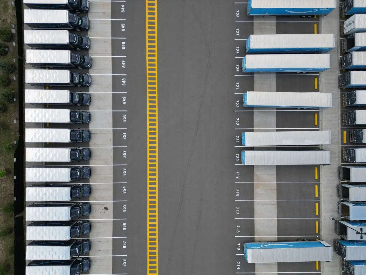 Rows of trucks lined up at a logistics parking lot seen from above.