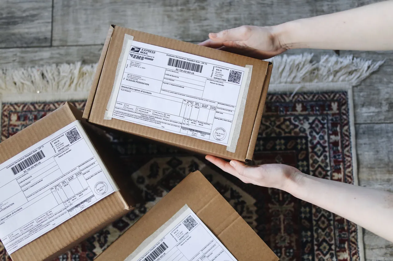 Top view of hands holding an express mail parcel with a customs declaration.