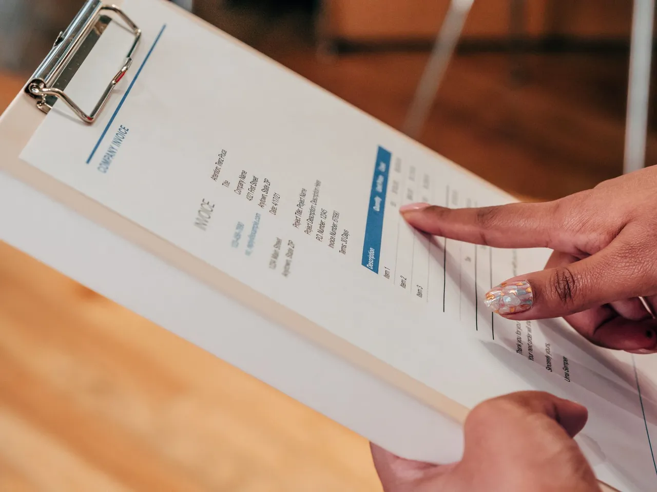 A person pointing at an invoice on a clipboard.